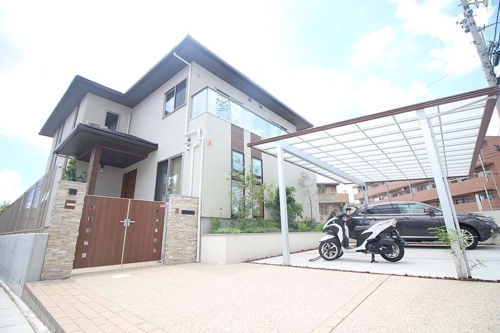 洋風モダンな外構に大型の二台用カーポートを設置。親しみやすい門扉を設置し、緑豊かな花壇も設置。